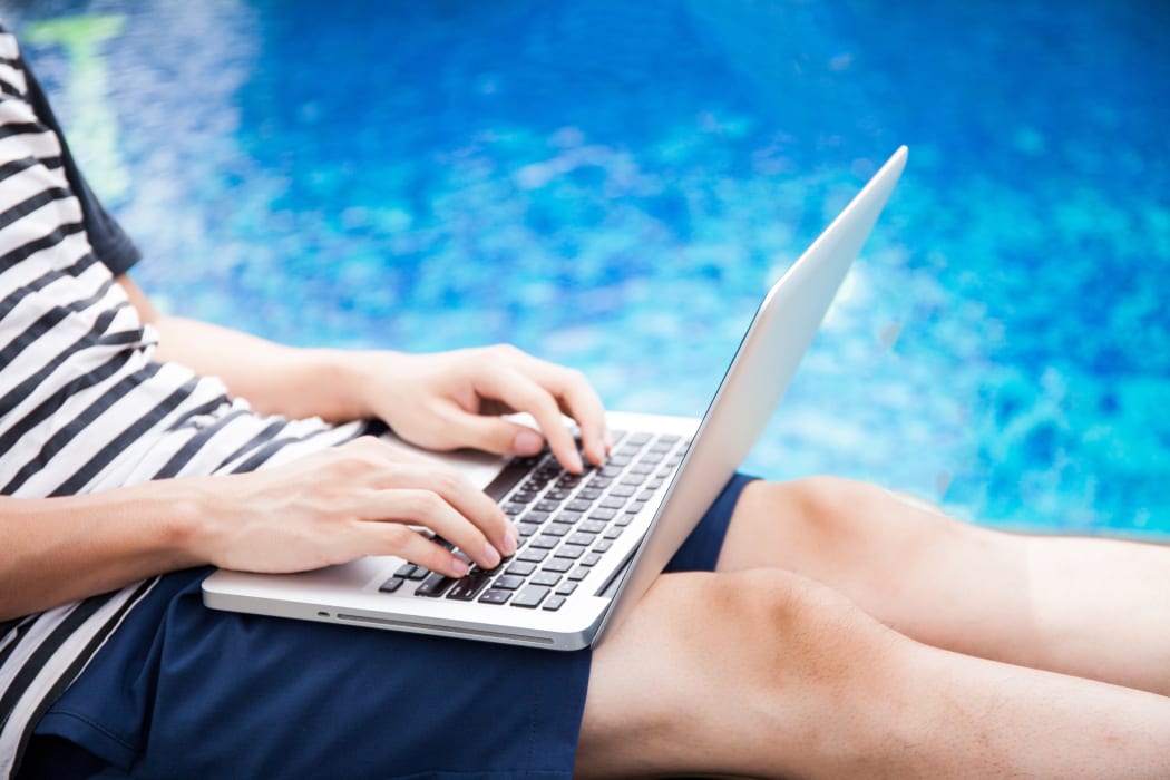 A man with a laptop checks his work emails by the pool (file).