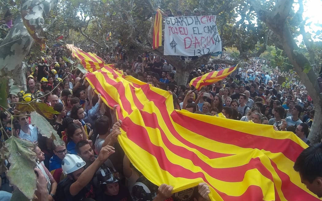 Thousands hold a Spanish flag made of cloth during a union strike held in Barcelona to denounce police violence during the Catalonia independence referendum.