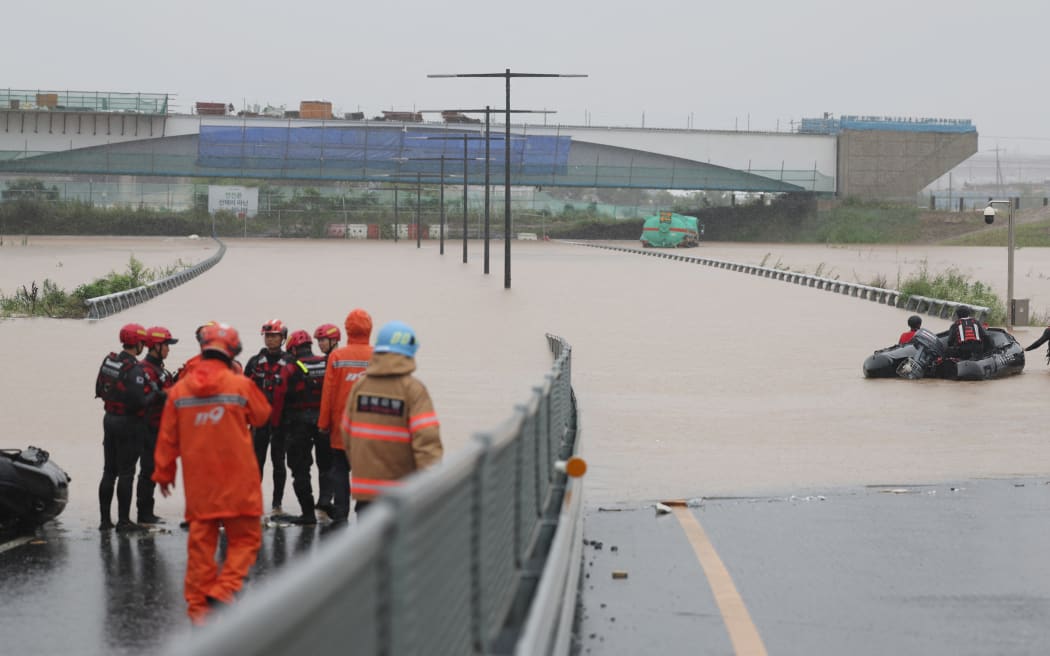 South Korean emergency workers search for survivors on a flooded road leading to an underground tunnel where some 19 cars were trapped by flood waters after heavy rains in Cheongju on July 15, 2023.
