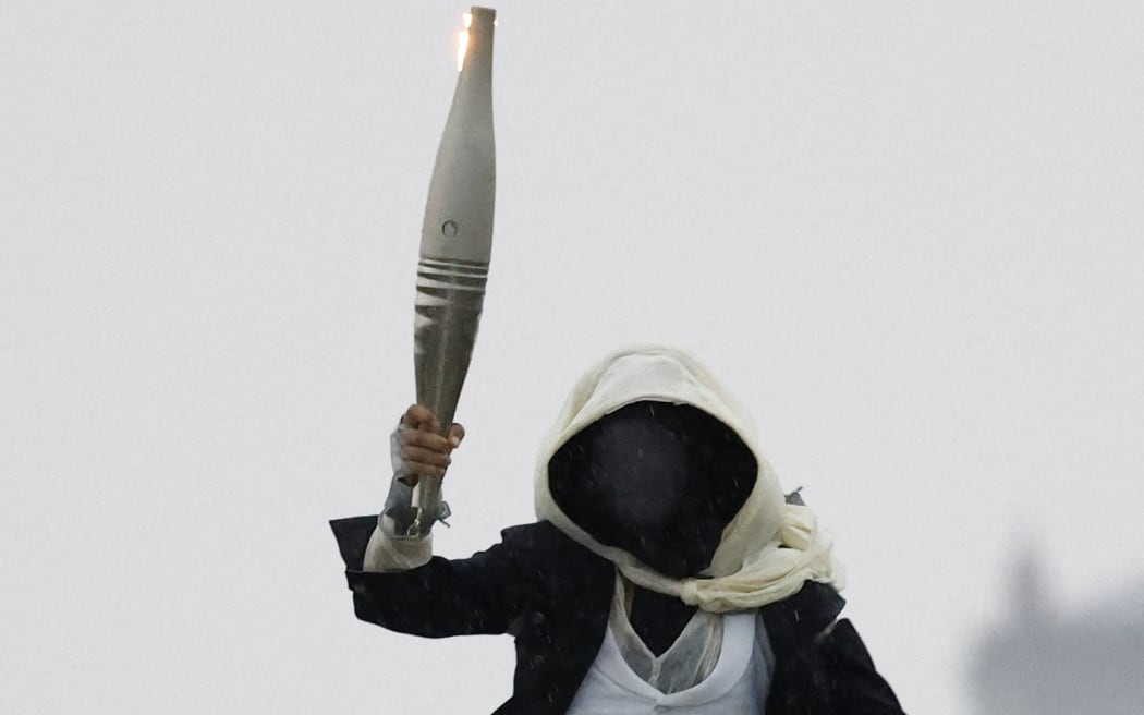 Paris 2024 Olympics - Opening Ceremony - Paris, France - July 26, 2024. A torchbearer runs atop the Musee d'Orsay during the opening ceremony. (Photo by Peter Cziborra / POOL / AFP)