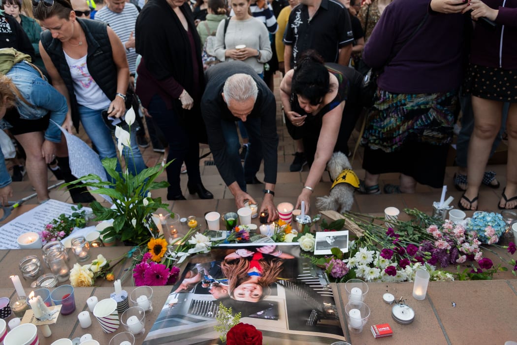 People place candles and flowers next to a photo of British backpacker Grace Millane during the vigil at Civic Square Park in Wellington.