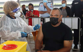 The Controller of the PNG National Pandemic Response, David Manning, receives a shot of the Covid-19 vaccine produced by Astrazeneca.