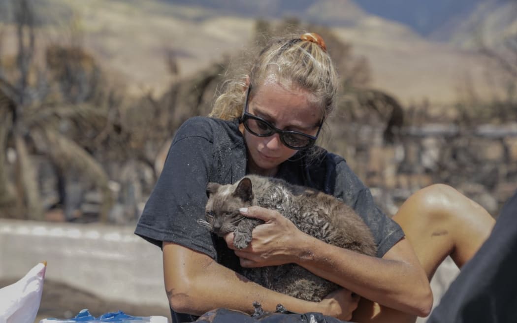 A woman cradles her cat after finding him in the aftermath of a wildfire in Lahaina, western Maui.