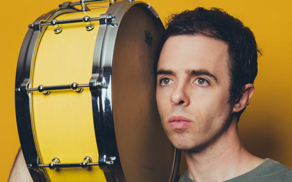 Publicity photo of American composer Daniel Temkin with a side drum on his shoulder.