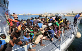 Illegal migrants from Africa sit on a Libyan coastguard boat as they arrive at a naval base in Tripoli after being rescued in the Mediterranean Sea, off the Libyan coast.