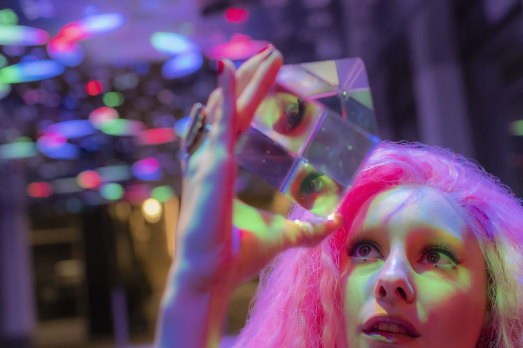 Woman with pink hair looking up at dimensional crystal cube. (Photo by Tom Merton/CAIA IMAGE/SCIENCE PH / NEW / Science Photo Library via AFP)