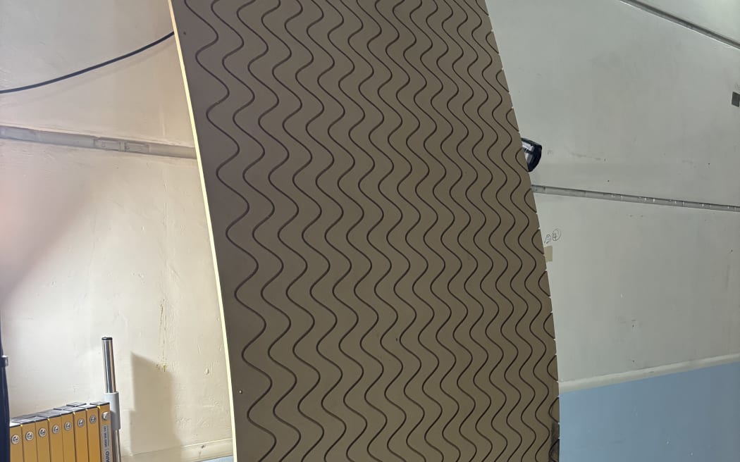 A piece of plywood with lines engraved vertically down. The engraved lines are designed to disrupt sound waves, minimising outside noise when installed in homes.