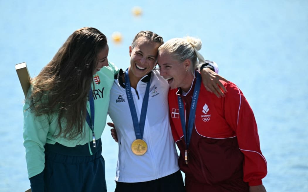 (From L) Hungary's silver medallist Tamara Csipes, New Zealand's gold medallist Lisa Carrington and Denmark's bronze medallist Emma Aastrand Jorgensen celebrate on the podium during the medal ceremony after the women's kayak single 500m final of the canoe sprint competition at Vaires-sur-Marne Nautical Stadium in Vaires-sur-Marne during the Paris 2024 Olympic Games on August 10, 2024. (Photo by Bertrand GUAY / AFP)