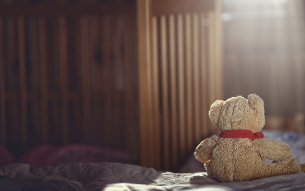 Teddy bear in an empty child's room.