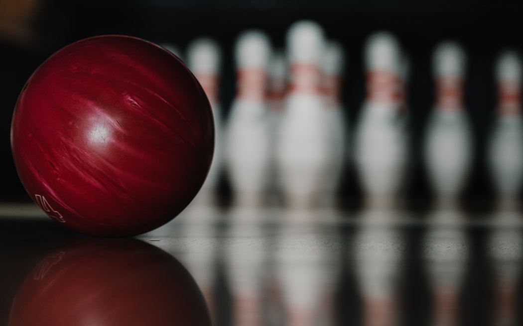 close-up shot of red bowling ball on alley in front of pins