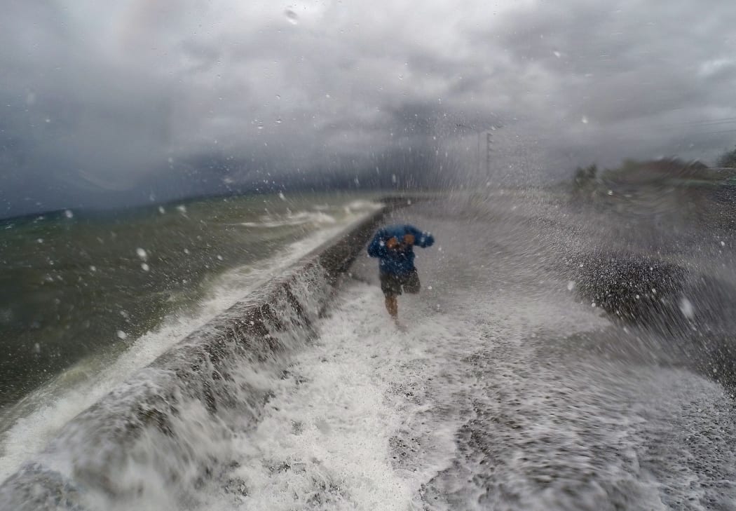 More than 700,000 people have fled as the storm approaches amid threats of giant waves, floods and landslides. Here, waves cross a coastal road in Legaspi, Albay, south of Manila on 14 December 2015.