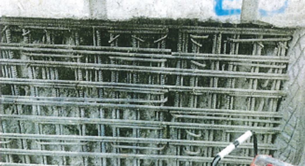 Steel reinforcing exposed by unsound concrete is prepared for repair, in the basement or near a wall.