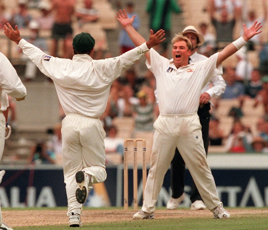 Australian spin bowler Shane Warne (R) raises his arms after claiming the wicket of a South African batsman on the way to his 300th wicket in Test cricket as Australia win the second Test Match in Sydney 05 January, 1998.