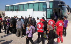 Syrian rebel fighters and their families, helped by Red Crescent, arrive in Idlib after being evacuated from Daraya.