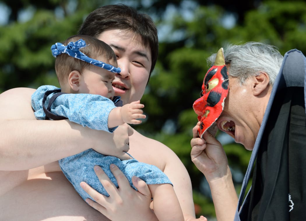 A referee encourages a baby to cry using a devil mask during last year's competition in Tokyo.