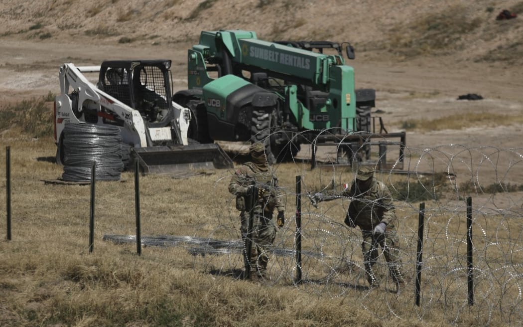 National Guard agents place a barbed wire wall on the banks of the Rio Grande in El Paso, Texas, on the border with Ciudad Juarez, Chihuahua State, Mexico, on March 8, 2023. (Photo by Herika Martinez / AFP)