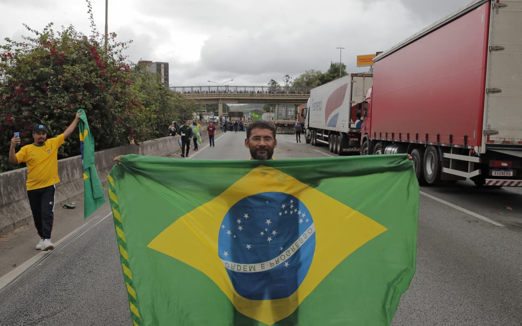 A supporter of President Jair Bolsonaro displays a Brazilian national flag during a blockade on Castelo Branco highway, on the outskirts of Sao Paulo, Brazil, 1 November 2022. -