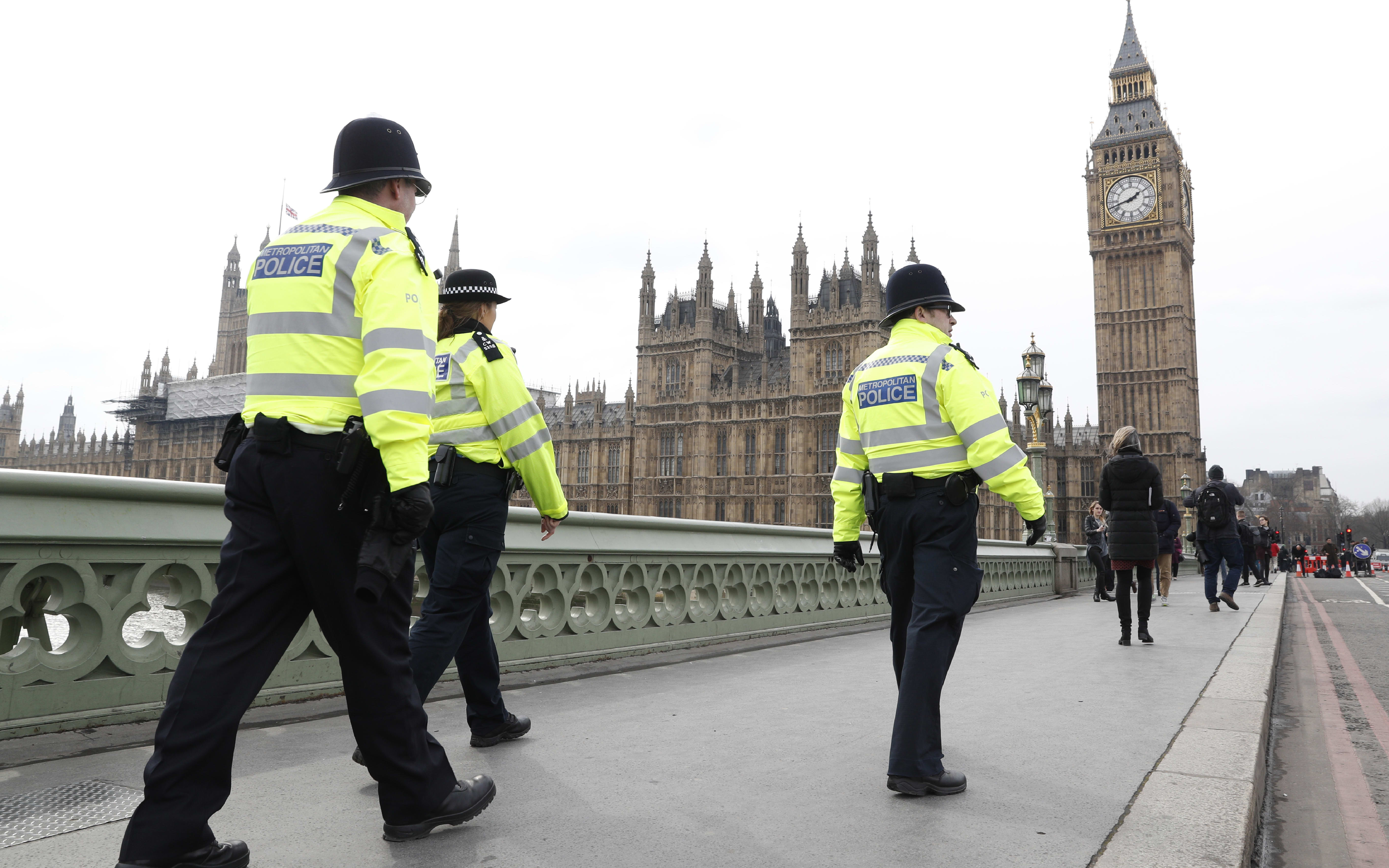 Police patrol across Westminster Bridge toward the Houses of Parliament.