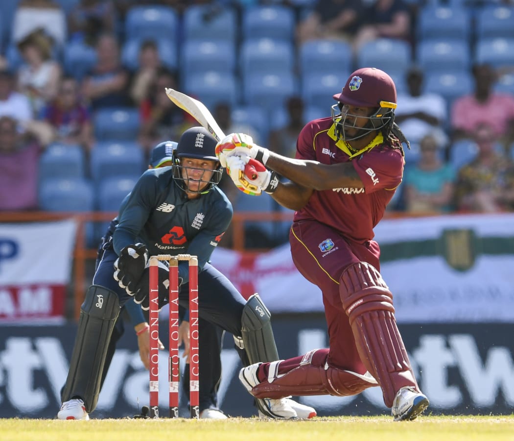 Chris Gayle (R) of West Indies hits a four as Jos Buttler (L) of England watches during the 4th ODI between West Indies and England in Grenada.