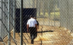 A Sept. 9, 2005 file photo of a guard walking inside the perimeter fence and razor wire that surrounds Villawood Detention Centre in Sydney.