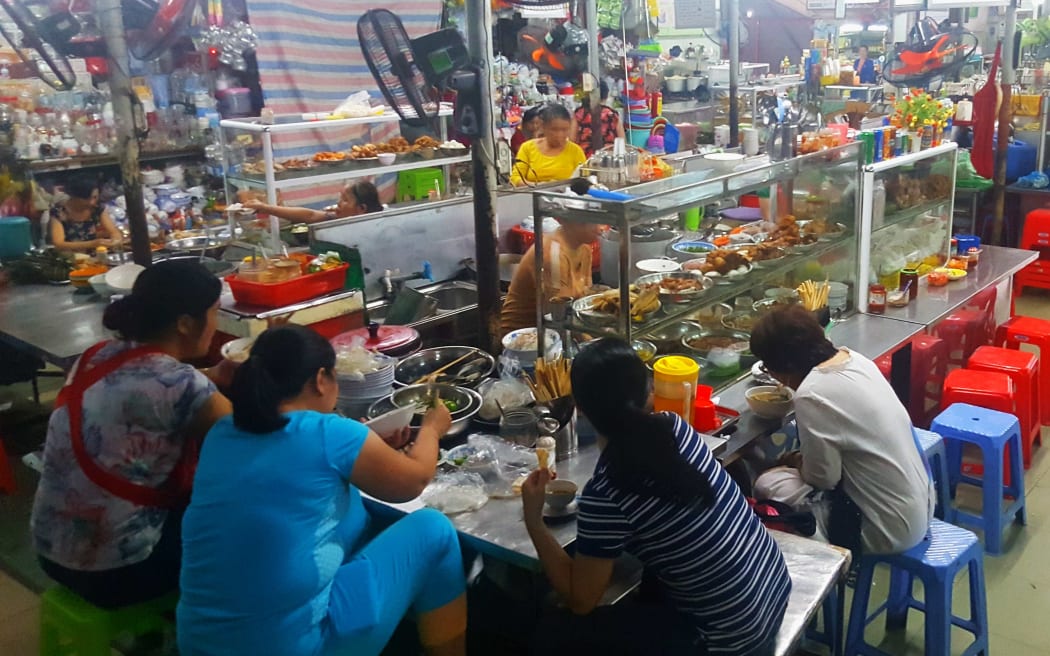 clinets eat at stainless steel bench around  food vendor