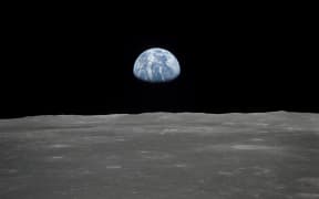 This July 1969 NASA file photo obtained July 16, 2019 shows a file view of Earth rising over the Moon's horizon taken from the Apollo 11 spacecraft. - The lunar terrain pictured is in the area of Smyth's Sea on the nearside.
