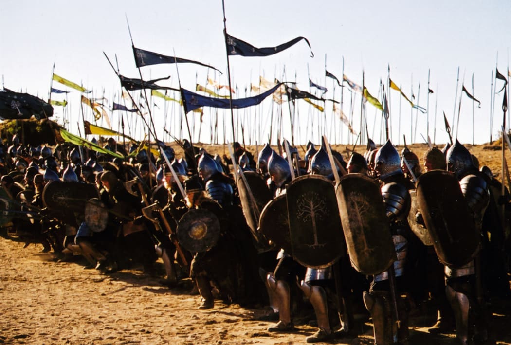 A still from Return of the King. The front lines of an army poised for battle, wearing shiny armour, carrying shields, and waving colourful banners.