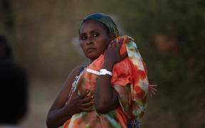 An Ethiopian refugee who fled fighting in Tigray province carries her baby as she walks at the Um Rakuba camp in Sudan's eastern Gedaref province, on November 21, 2020.