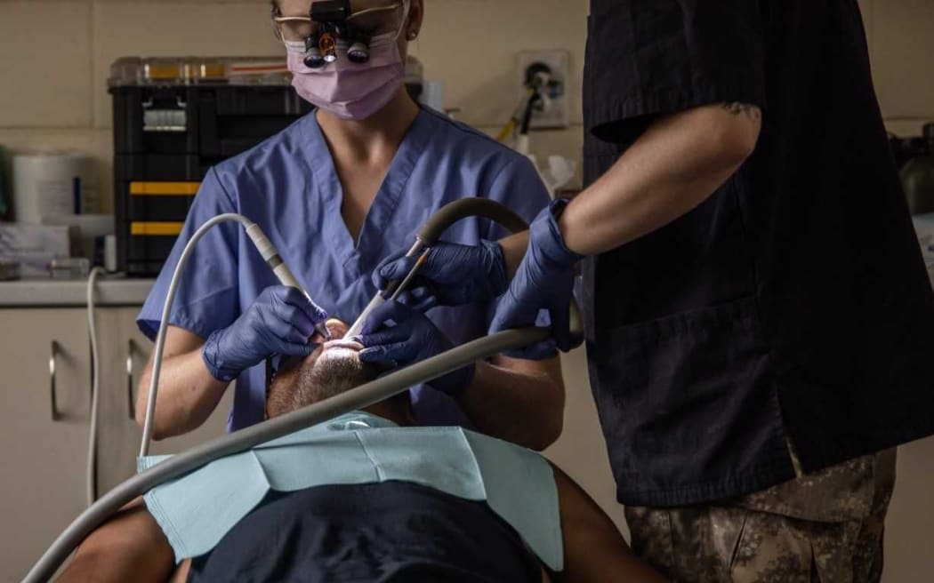 Dentist Lieutenant Amanda Rowe (left), assisted by a NZDF Dental Assistant, treats a patient in Samoa