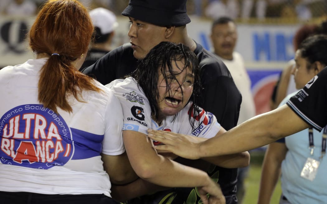 A woman is held by other as she cries following a stampede during a football match between Alianza and FAS at Cuscatlán stadium in San Salvador, on 20 May, 2023. At least nine people were killed in the stampede, police said.