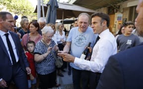 France's President Emmanuel Macron (R) is offered a bottle of wine as he meets residents of Baumes-de-Venise, Southeastern France on September 1, 2023, during a one-day trip focused on the reform of vocational high schools. (Photo by Ludovic MARIN / POOL / AFP)
