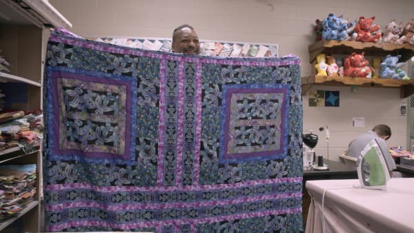 Missouri maximum security prisoner Chill, in Netflix documentary The Quilters, directed by Jennifer McShane, smiles as he holds up a quilted piece he's made.