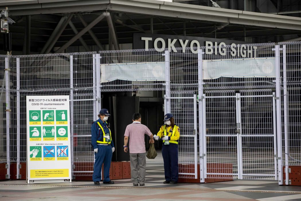 Security personnel check the accreditation and body temperature of a man entering Tokyo Big Sight.