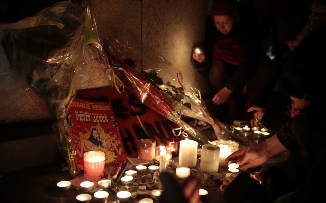 People light candles in front of an issue of Charlie Hebdo at the Place de la Republique, Paris.