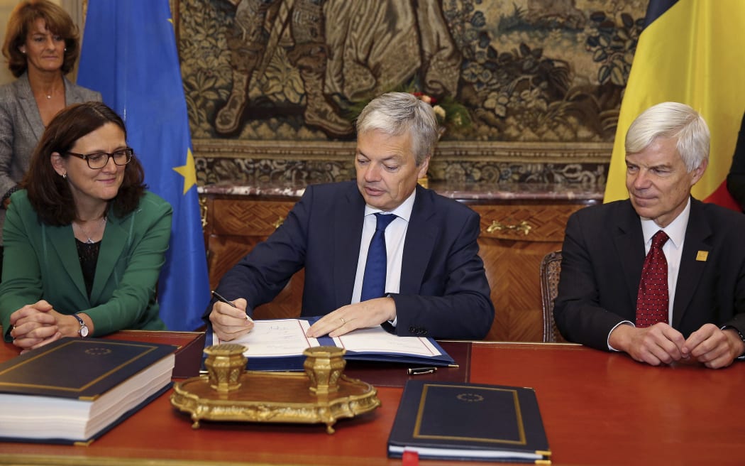 Vice-Prime Minister and Foreign Minister Didier Reynders (C) signs next to European Commissioner for Trade Cecilia Malmstrom (L) and Candian Ambassador Olivier Nicoloff (R) during the signing ceremony by Belgium of the EU-Canada Comprehensive Economic and Trade Agreement (CETA) on October 29, 2016