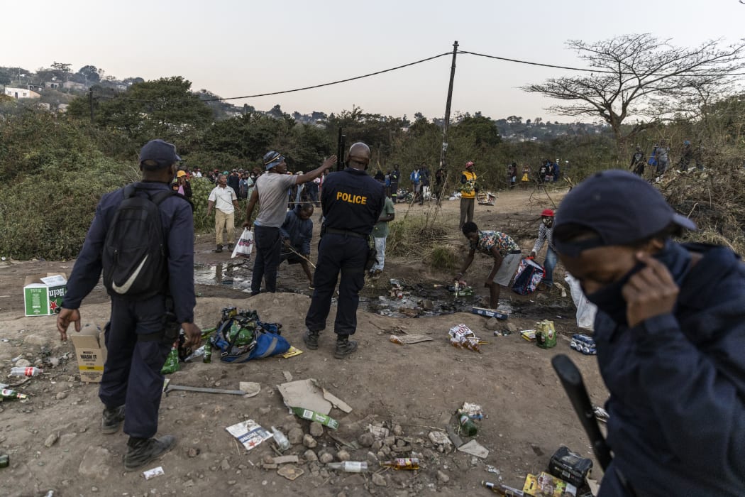 Police officers argue with members of the community next to a looted  warehouse storing alcohol in Durban on July 16, 2021,