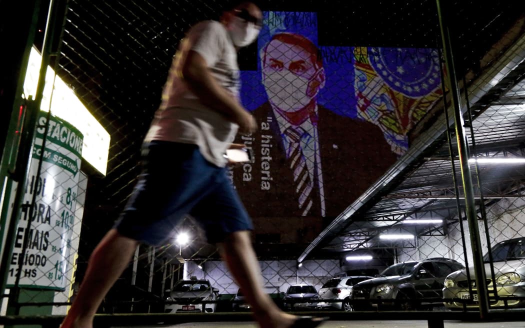 An image of Brazil's President Jair Bolsonaro wearing a protective face mask and the phrase Hysteria Damages the Economy" is projected on the wall of a building as a protest against the president regarding his handling of the coronavirus COVID-19 outbreak, in Sao Paulo, Brazil, March 21, 2020.