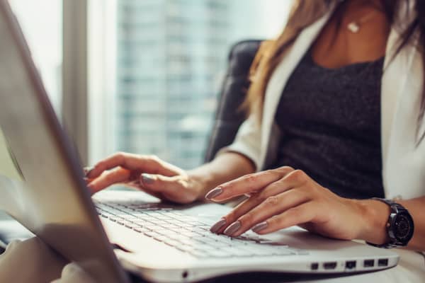 Close-up view of hands on keyboard woman using netbook sitting in office.