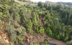 A drone image captures the massive slip at Helena Bay Hill in Northland, cutting off Ōakura Bay.