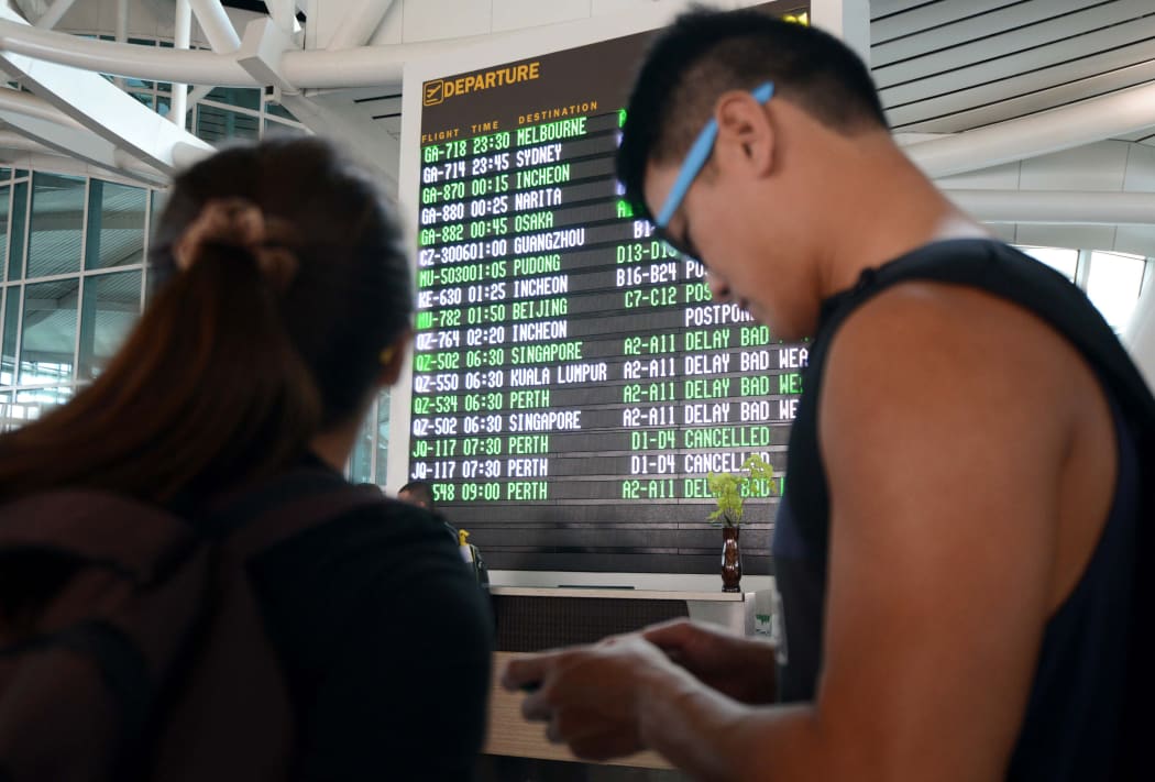 Passengers check flight information in the international terminal at Bali's Ngurah Rai airport in Denpasar.