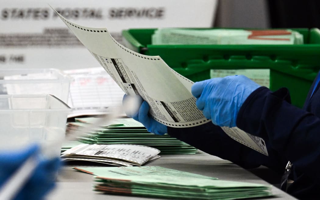 A US election worker removes a ballot from an envelope to count and inspect the pages on the countries 2024 Election Day, 5 November, in Phoenix, Arizona.