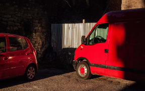 red van and city car parked in the shadows of the buildings. (Photo by: Marco Scataglini/UCG/Universal Images Group via Getty Images)