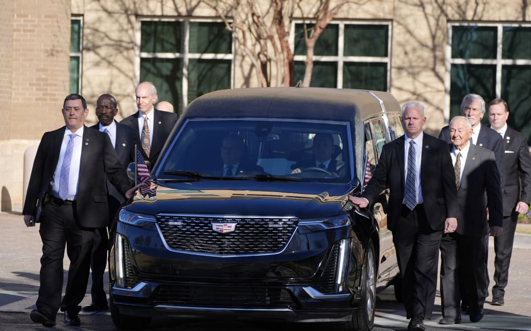 Former and current US Secret Service agents assigned to the Carter detail, walk with the hearse carrying the flag-draped casket of former President Jimmy Carter, at Phoebe Sumter Medical Center on 4 January 4, 2025 in Americus, Georgia.