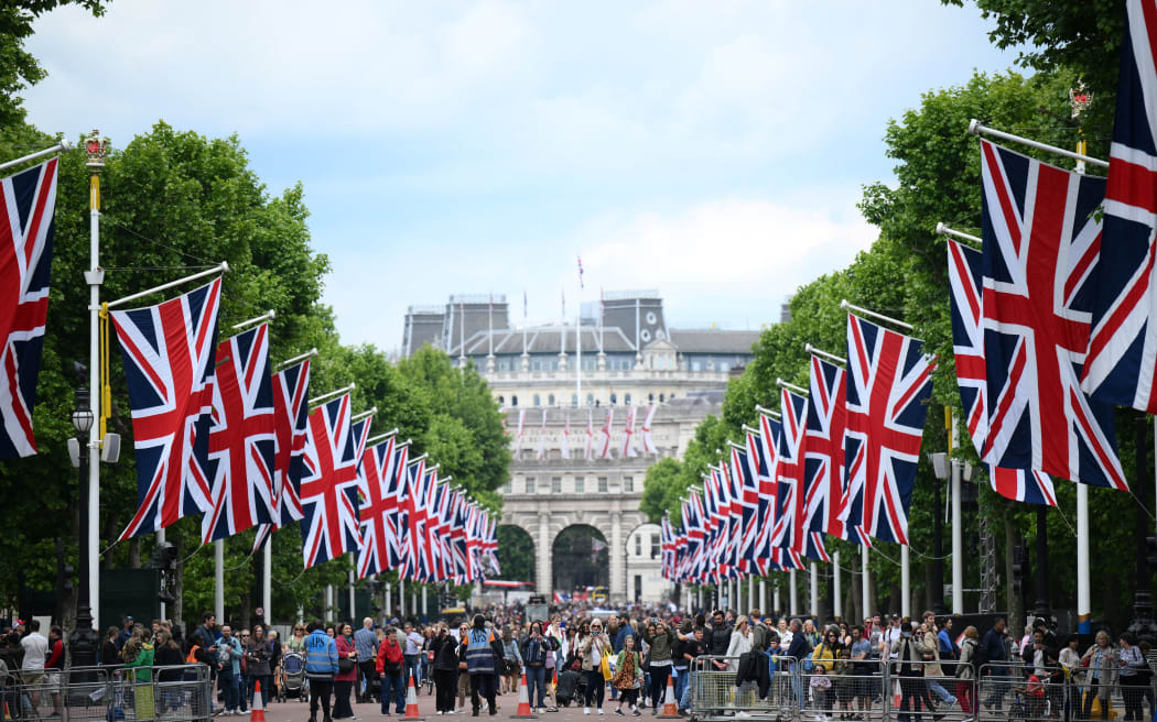 People gather of The Mall, in London, on June 1, 2022 as the Union flags flutter in the wind ahead of the Platinum Jubilee's celebrations for Britain's Queen. - Britain's Queen Elizabeth II has been on the throne since she was 25, an ever-present figure for the lives of most people in Britain, as well as one of the most recognisable people around the world. She will celebrate her Platinum Jubilee over four days from Thursday June 2nd, for her 70 years of reign. (Photo by Daniel LEAL / AFP)