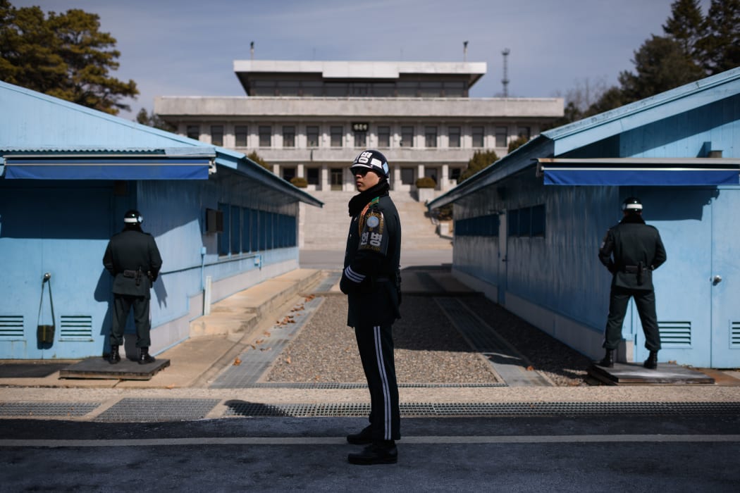 A South Korean soldier (C) stands guard before the military demarcation line and North Korea's Panmun Hall, in the truce village of Panmunjom, within the Demilitarized Zone (DMZ) dividing the two Koreas on February 21, 2018. / AFP PHOTO / Ed JONES