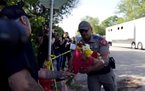 A police officer takes flowers from a resident to be placed at a makeshift memorial outside Robb Elementary School in Uvalde, Texas, on May 25, 2022.