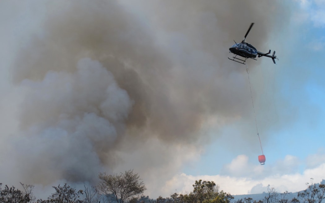 A helicopter equipped with a monsoon bucket battles an earlier fire at Mangakahia Road, south of Kaikohe (file photo).