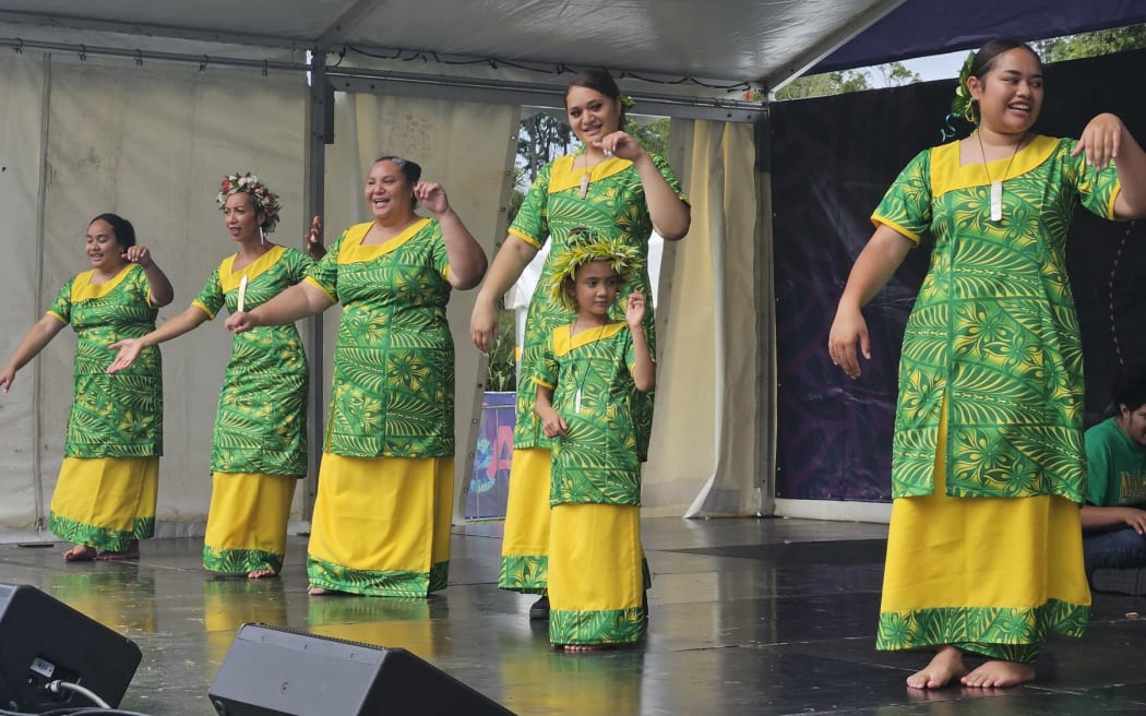 A group of Tokelau ladies share the stage with a young one who has expressed great interest in her cultural dance practices.