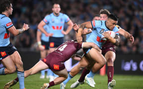 Spencer Leniu of the Blues is tackled by Harry Grant and Patrick Carrigan of the Maroons during Game 1 of the State of Origin 2024.