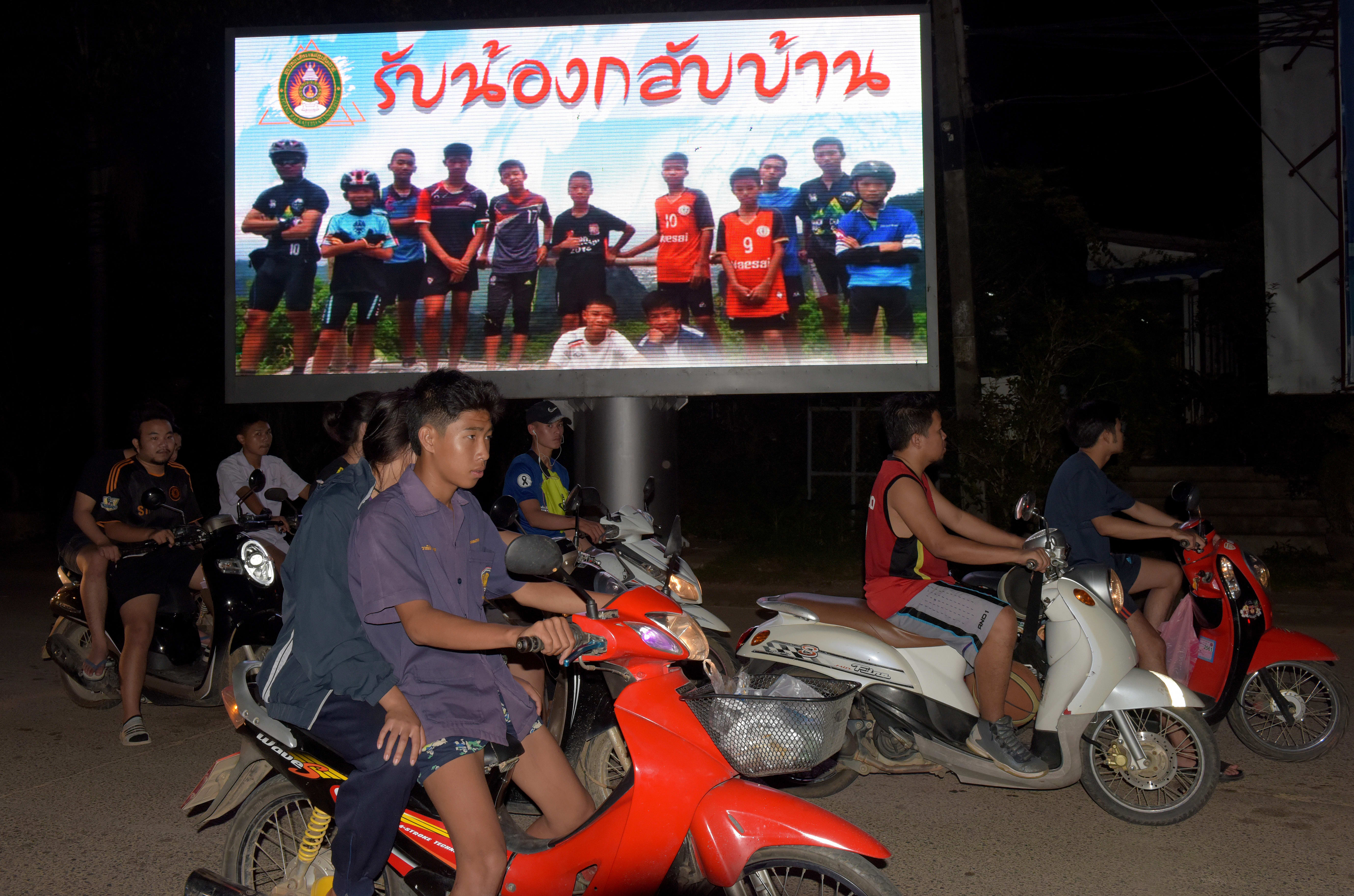 A billboard with a photograph of  members of the football team and their coach reads 'welcome home brothers'.